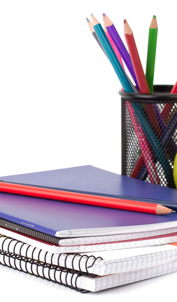Notebooks, pencils and a green apple on a white background