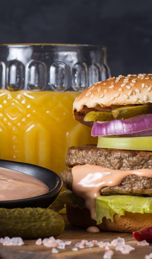 Аппетитный гамбургер на столе с соусом, овощами и соком