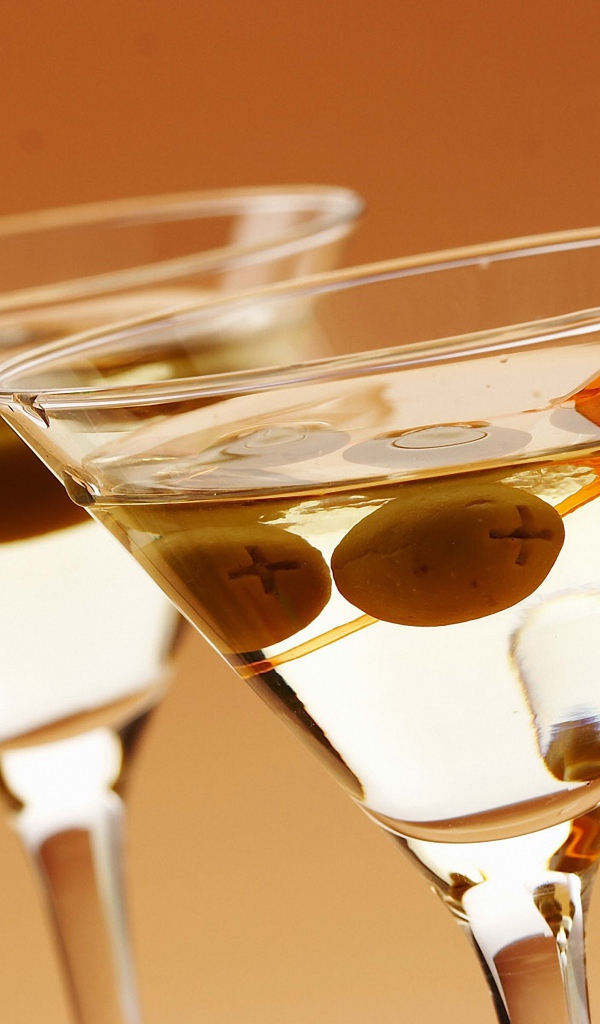 Напиток мартини в бокалах с оливками на кремовом фоне
