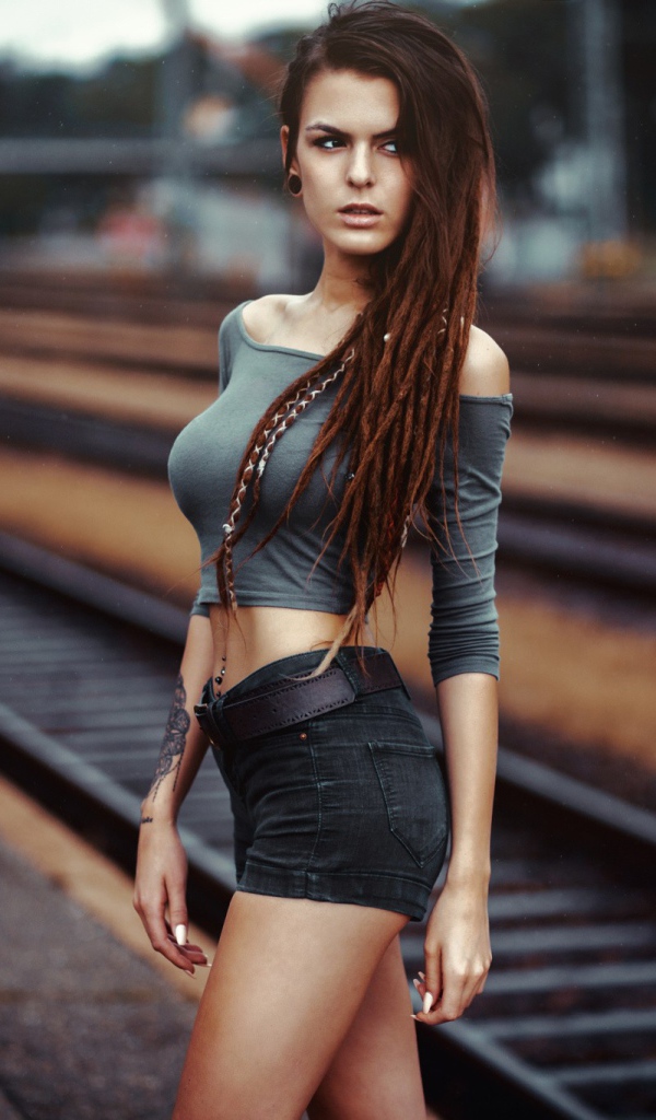 A beautiful slim model girl is standing by the railroad
