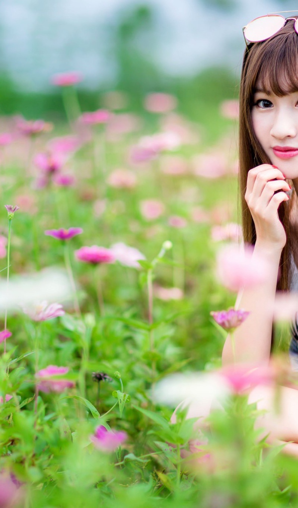Красивая девушка модель азиатка на поле с розовыми цветами