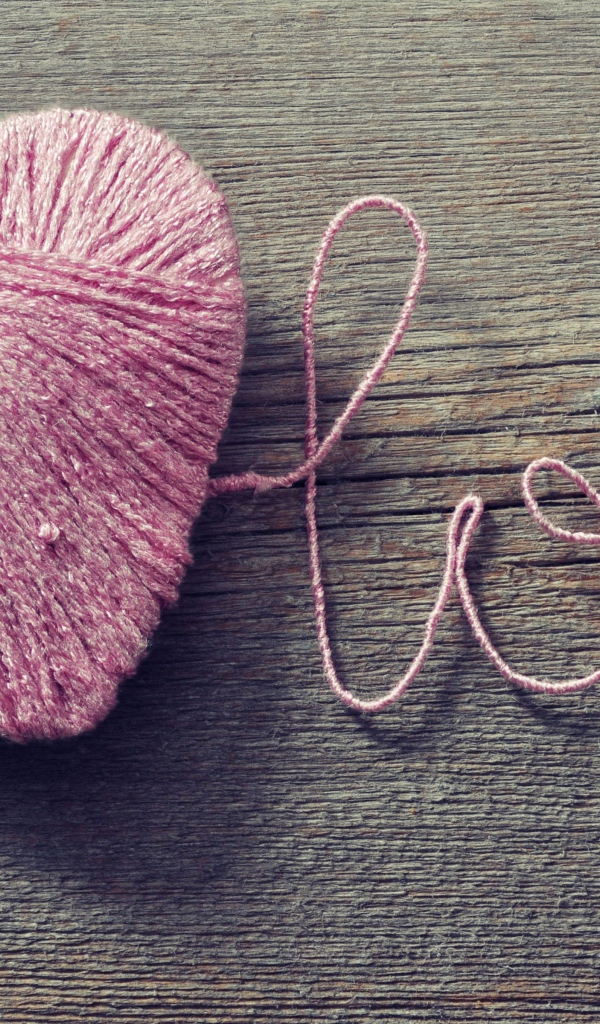 Надпись Love из розовых ниток на деревянном столе