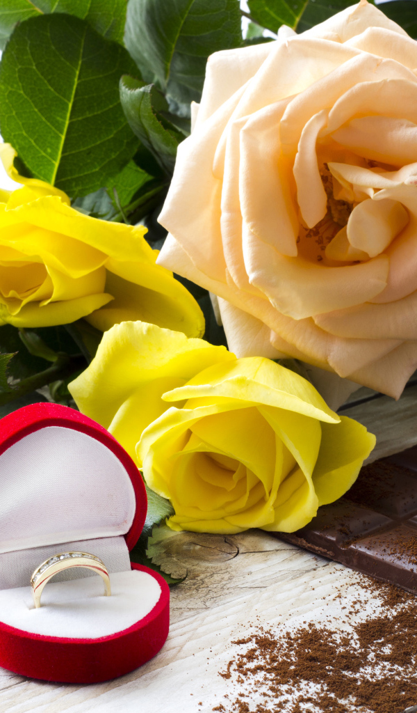 Букет роз на столе с шоколадкой и красной коробочкой с обручальным кольцом