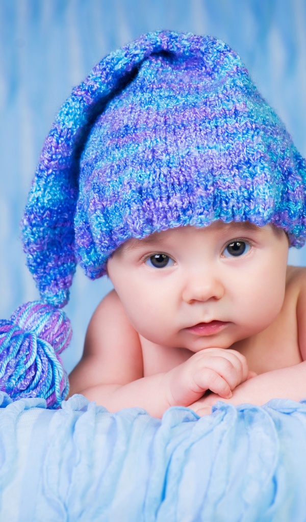 Грудной ребенок в красивой вязаной синей шапке