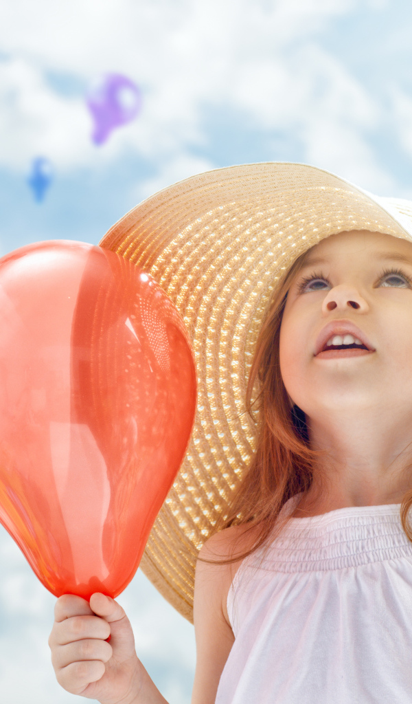 Милая маленькая девочка в большой шляпе с воздушным шариком в руке