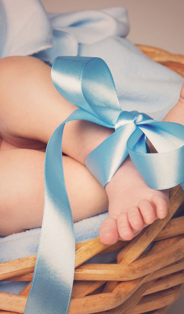Маленькие ноги младенца с голубым бантом