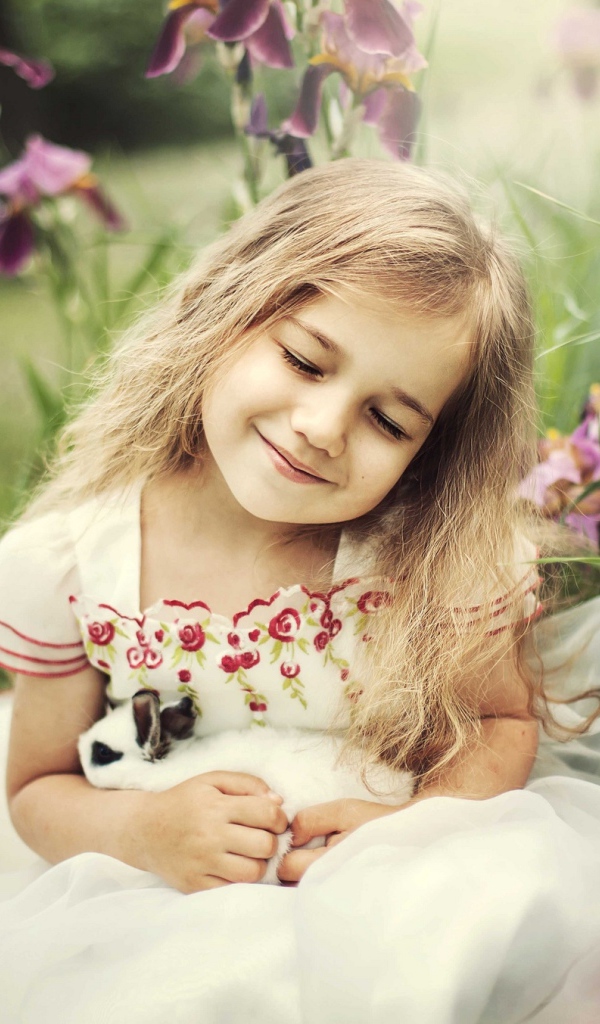 Маленькая девочка блондинка держит в руках кролика