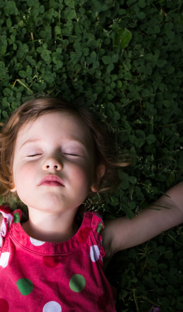 Маленькая девочка спит на зеленой траве 