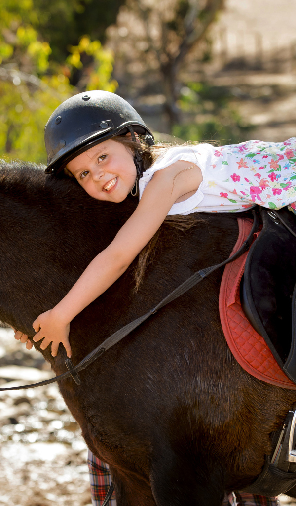 Маленькая девочка в шлеме верхом на пони