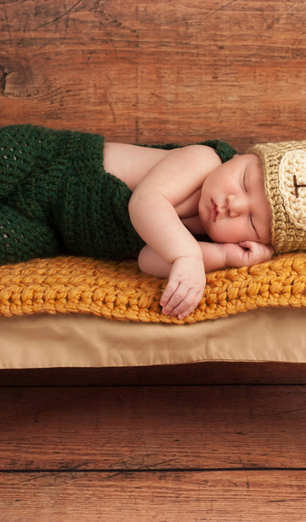 Новорожденный ребенок в костюме медвежонка спит на крошечной кровати