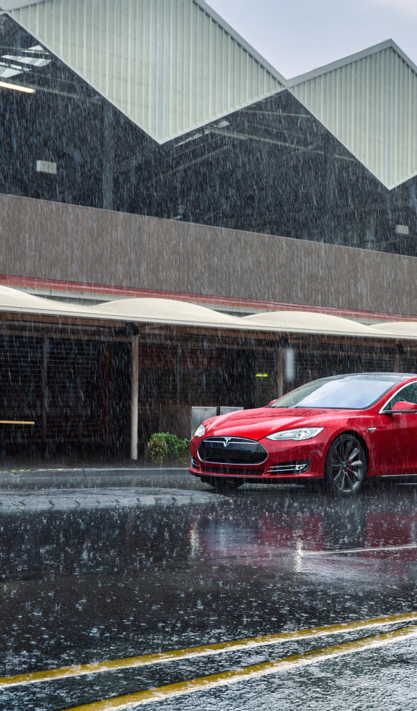 Красный автомобиль  Tesla Model S на дороге под дождем