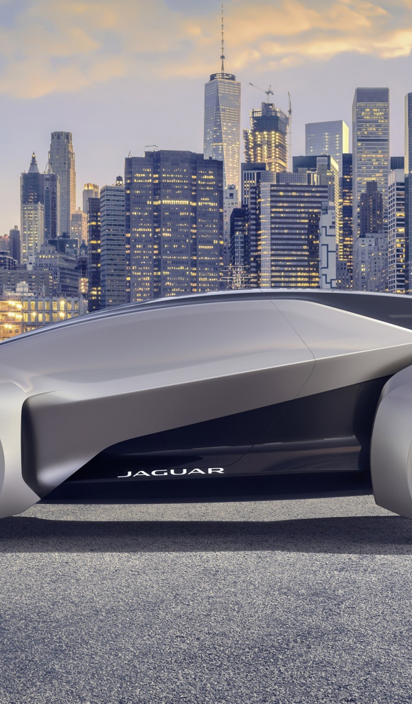 Серебристый электрический автомобиль  Jaguar Future-Type на фоне небоскребов
