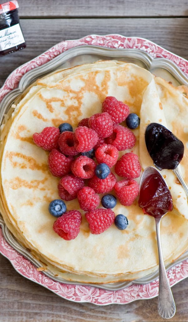 Thin pancakes with raspberries and blueberries on the table top view