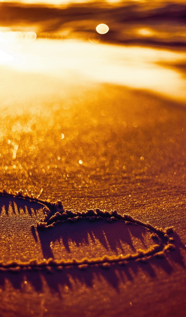 Нарисованное сердце на песке в лучах солнца