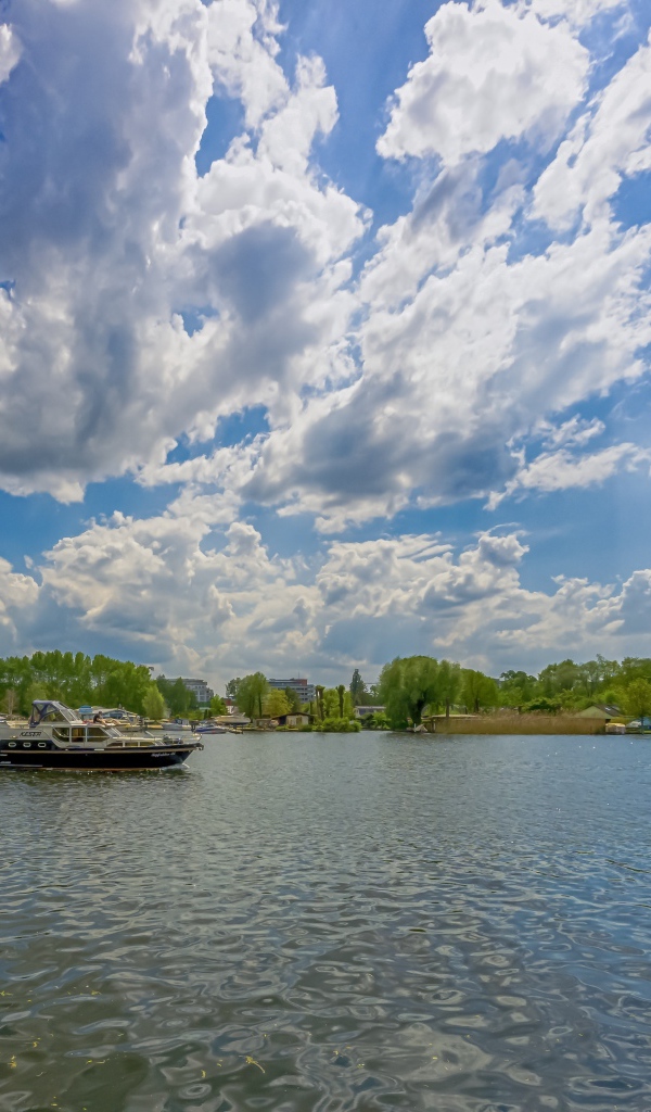 Катер на озере под красивым голубым небом с белыми облаками
