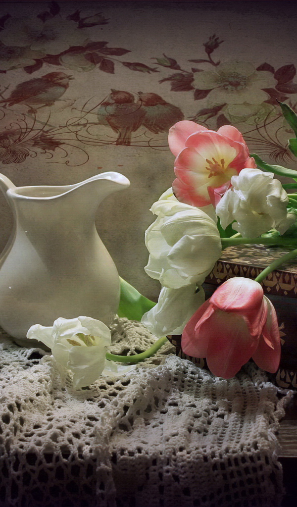 Bouquet of pink and white tulips on a table with a jug