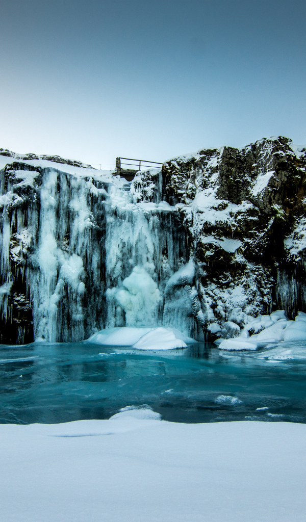 Замерзший водопад стекает со скалы зимой