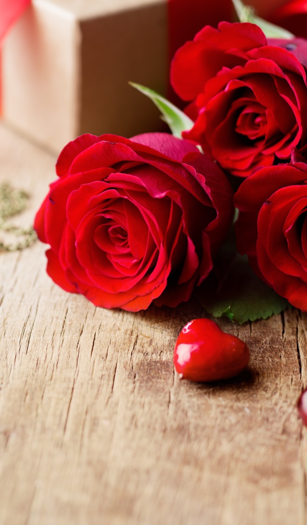 Три красивые красные розы на столе с сердечками и ключами
