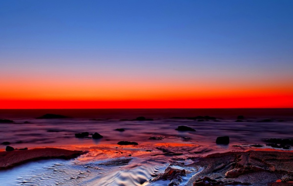 Голубое небо и красный закат на берегу моря
