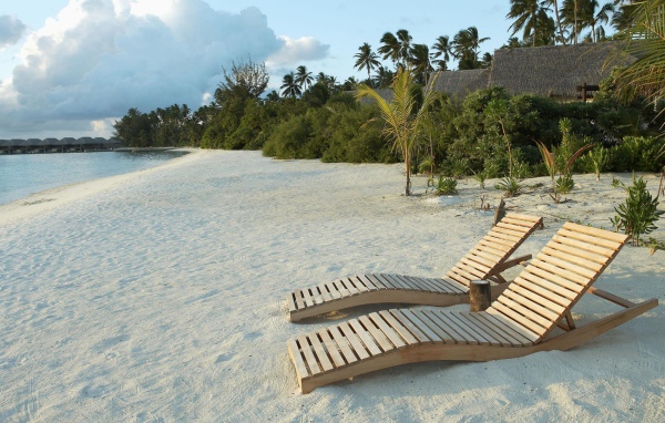 Деревянные шезлонги на белом песке пляжа