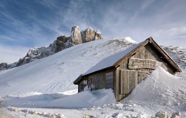 Деревянный домик замело снегом в горах