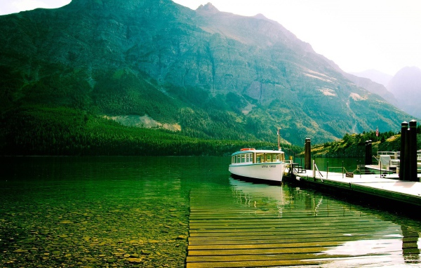 Лодка у причала на зеленой воде горного озера