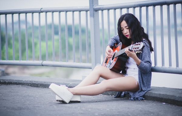Азиатка брюнетка с гитарой на мосту