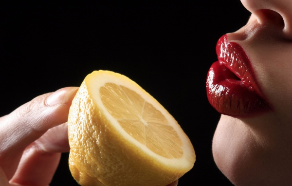 Девушка поднесла лимон к губам