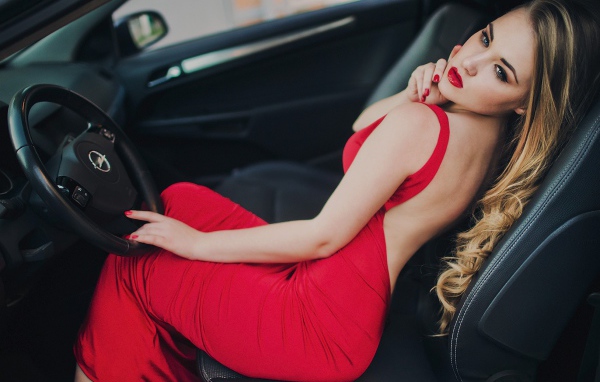 Красивая девушка в красном платье за рулем
