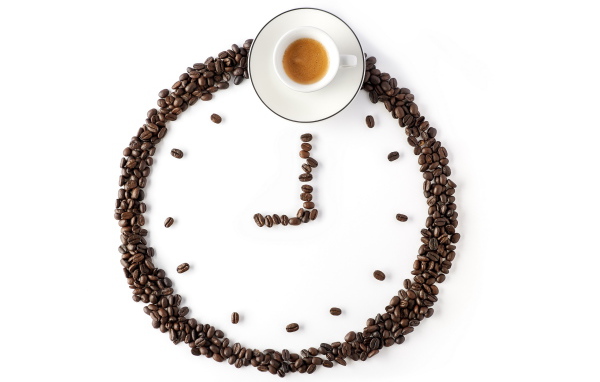 Часы из кофейных зерен и чашка кофе на белом фоне