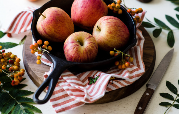 Красивые красные яблоки на сковороде с ягодами рябины