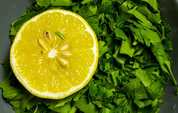 Половина желтого лимона с зеленью петрушки