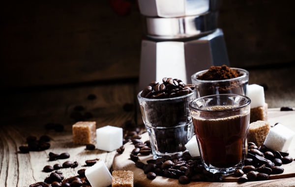 Стаканы с кофе, кофейными зернами и перемолотым кофе на столе с кубиками сахара