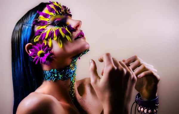 Девушка с украшенным лепестками цветов лицом и ярким макияжем