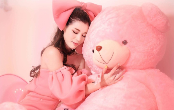 Красивая девушка азиатка с большим розовым медведем