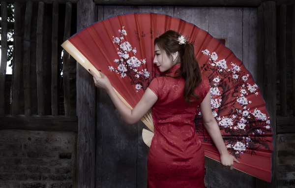 Красивая девушка азиатка в красном платье с большим веером