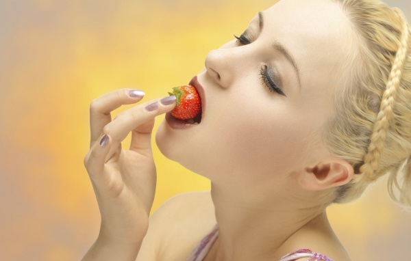 Девушка блондинка ест клубнику