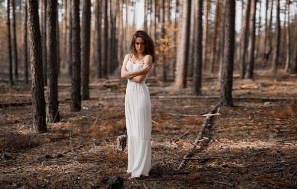 Молодая девушка в белом платье в лесу 