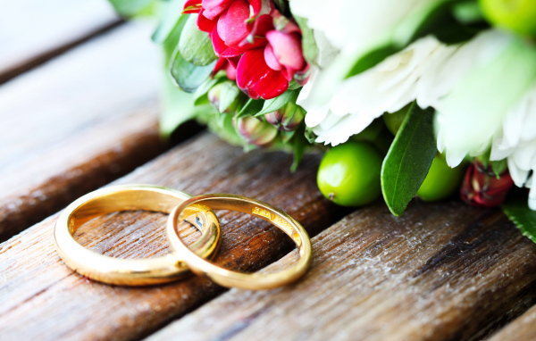 Два золотых обручальных кольца с букетом цветов