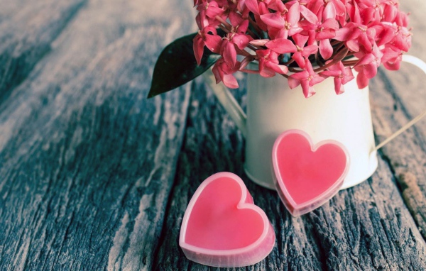 Pink flowers in a white vase and two pink hearts