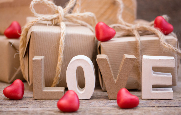 Романтические подарки и надпись Love с красными сердечками