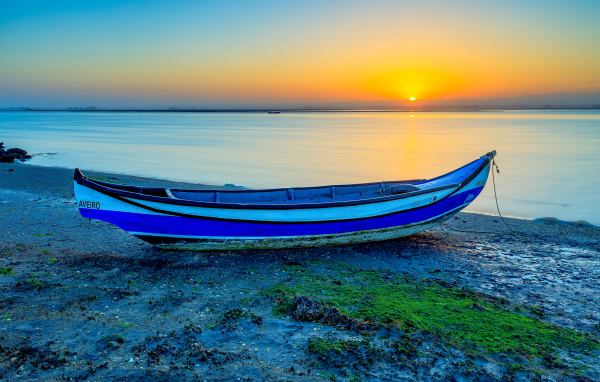Лодка на берегу реки на закате солнца