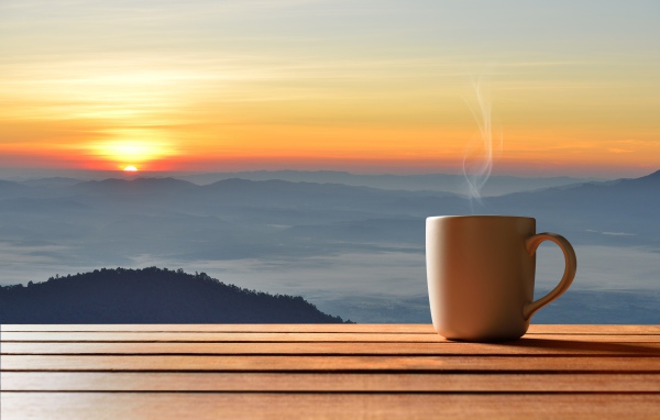 Чашка фоне на фоне горизонта с восходящим солнцем