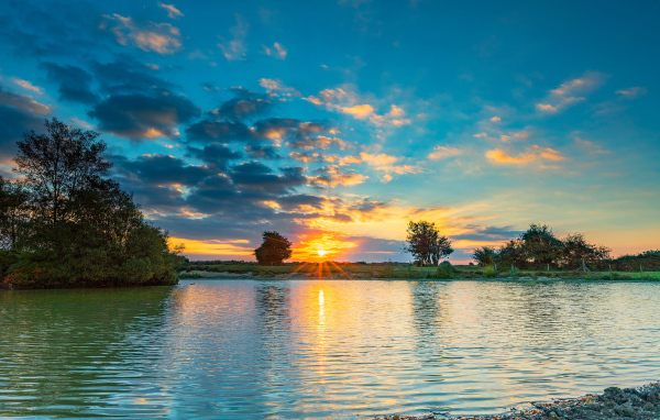 Закат солнца в небе отражается в воде озера 