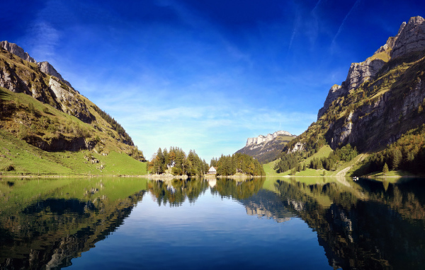 Горы отражаются в воде озера под красивым голубым небом, Швейцария