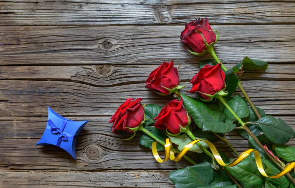 Букет красных роз на столе с синей коробочкой