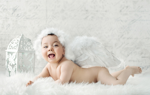 Забавный улыбающийся ребенок с крыльями ангела