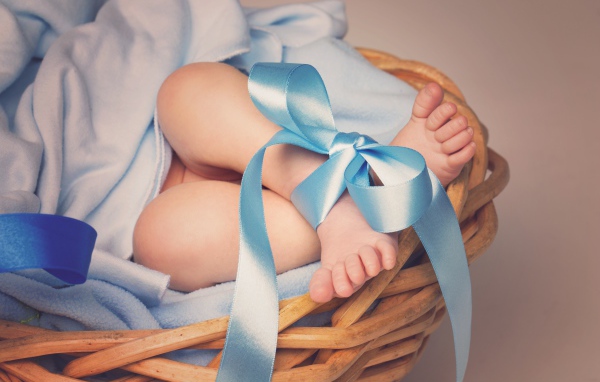 Маленькие ноги младенца с голубым бантом