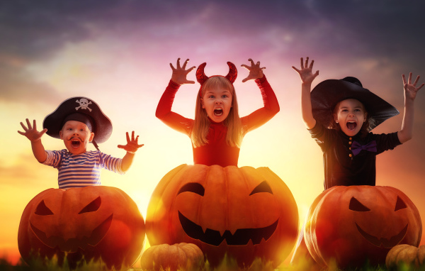 Маленькие дети в костюмах на Хэллоуин с большими тыквами