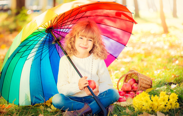Smiling girl sitting under a colorful umbrella